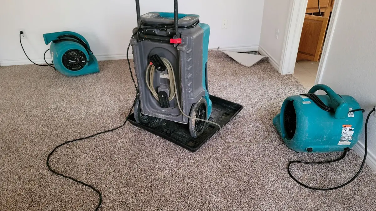 Air movers and a dehumidifier drying a carpeted room
